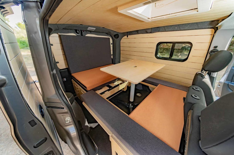 interno di un furgone con sedile a panchina e tavolo in legno