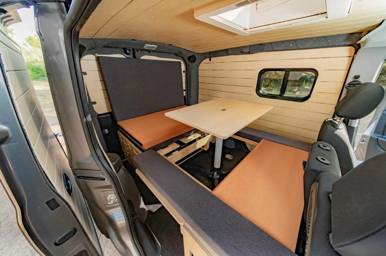 interno di un furgone con arredi in legno, un tavolo e una scatola