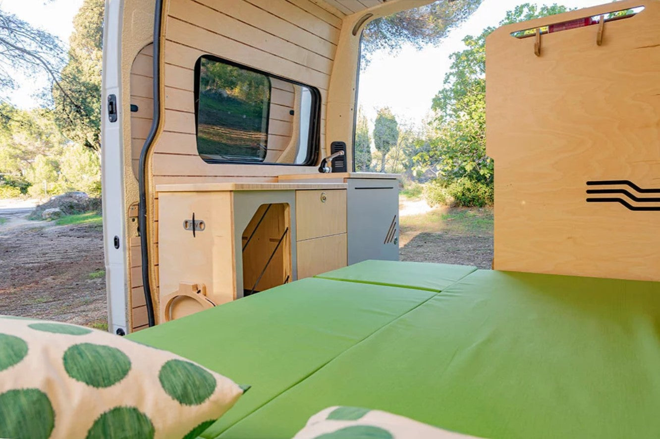 letto completamente dispiegato con materasso verde in un furgone riconvertito