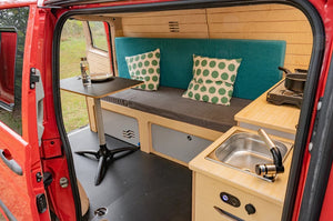 Allestimento di van con letto e tavolo in un furgone rosso