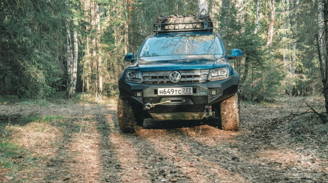 Vista frontale di un AMAROK blu con paraurti Rival in un bosco di abeti