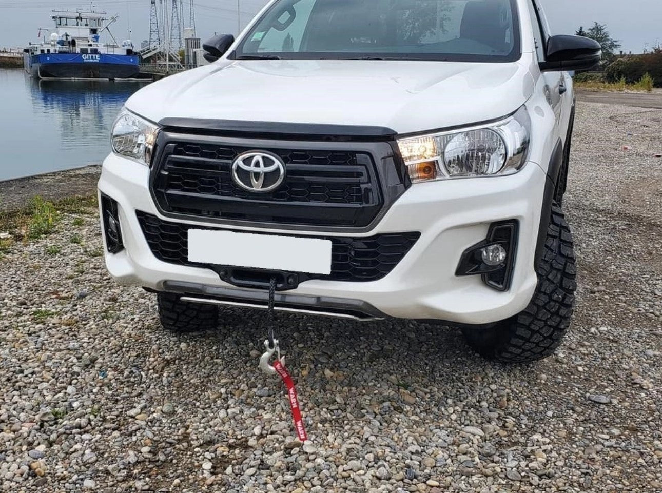 Toyota bianca di fronte a una barca con un cavo sporgente