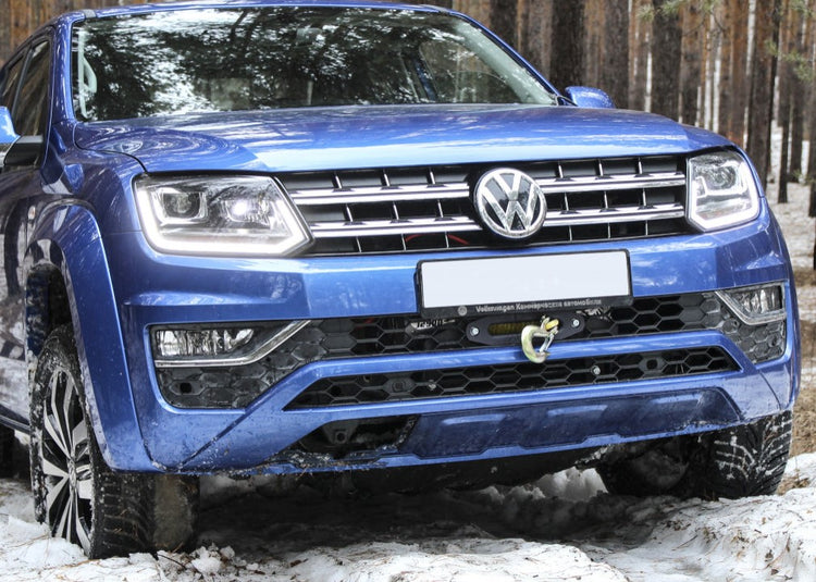 vista frontale di un Amarok blu nella neve e nel bosco