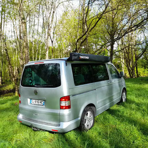 Volkswagen Transporter grigio parcheggiato sull'erba con un tendalino chiuso e in ordine