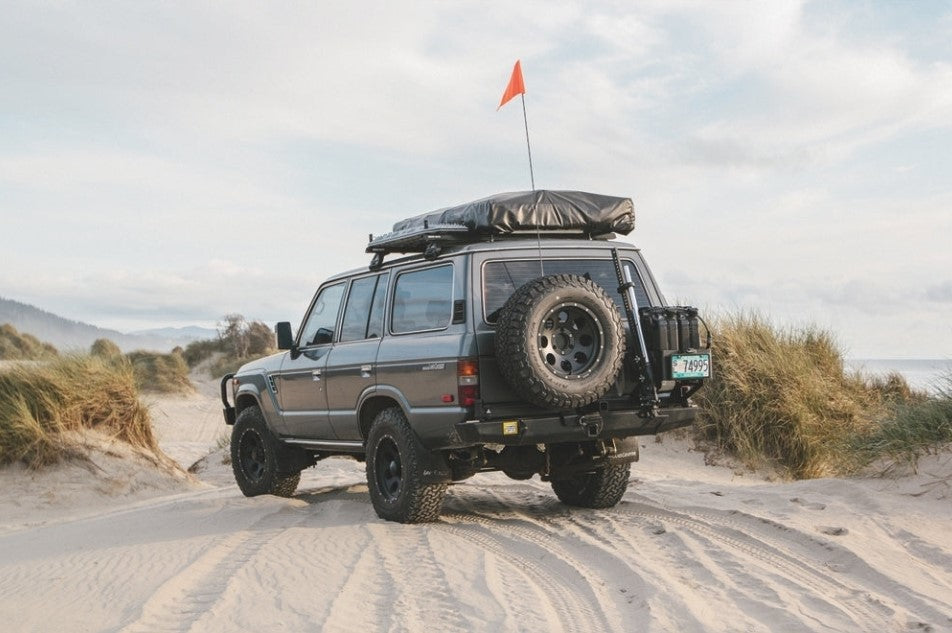 toyota 4x4 nella sabbia con una tenda da tetto nera