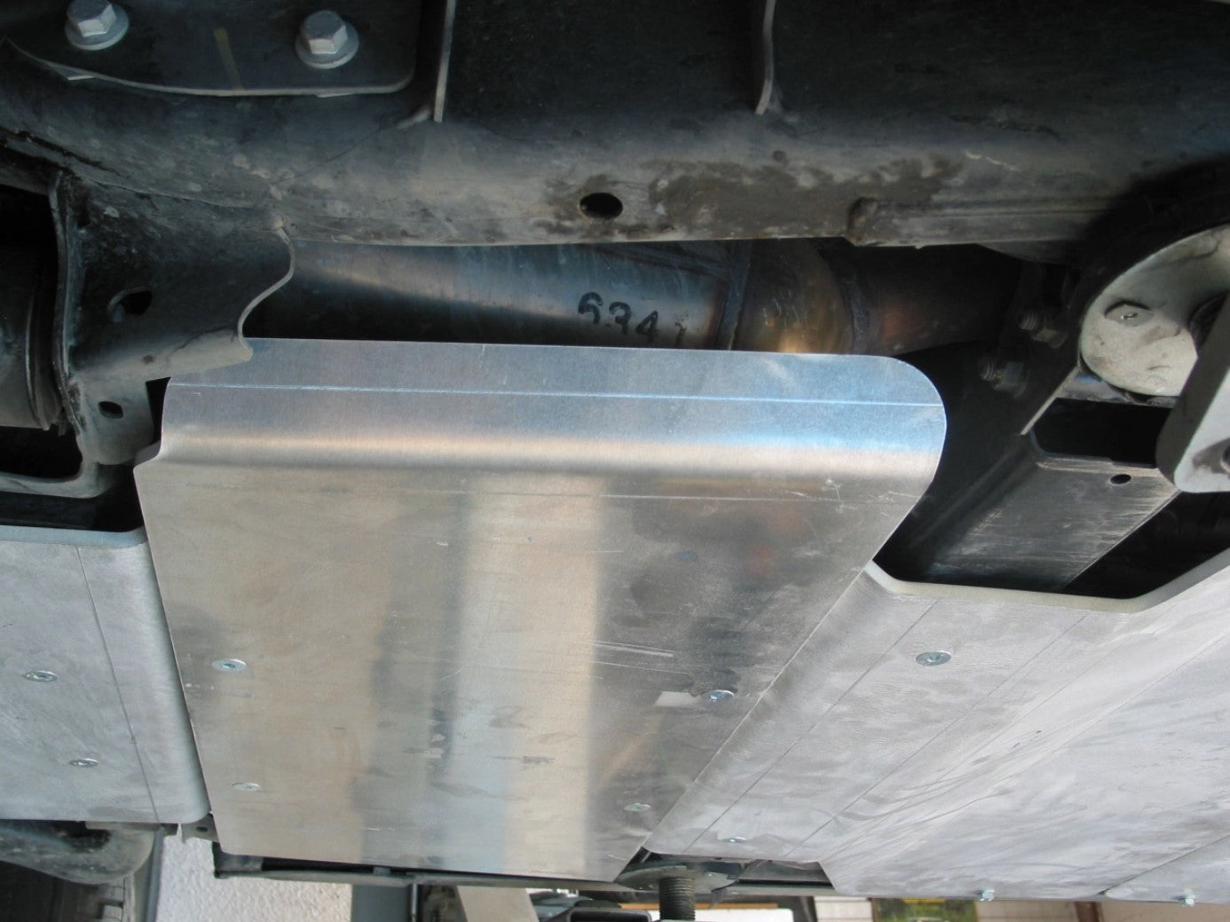 sci protettivo in alluminio attaccato alla parte inferiore di un veicolo tra due