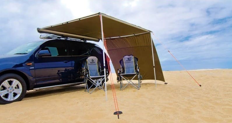 Bivacco all'aperto sulla sabbia sotto una tenda marrone